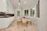 Custom white cabinetry with glass-panel upper doors, dark stone countertops, recessed lighting, multi-pane windows, and tile flooring with decorative 