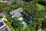 Aerial perspective of a multi-level estate featuring a tile roof, an in-ground swimming pool, stone-paver hardscaping, mature landscaping, and an expa