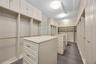 Custom built-in cabinetry featuring white shaker-style doors, dual islands with stone-composite countertops, matte gold hardware, tiered shelving, and