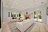 Living area featuring stone flooring, a decorative stone fireplace mantle, recessed tray ceiling, and multiple sets of glass-paned French doors