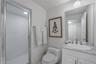 Staff Suite: Bathroom featuring a stone-top vanity with an integrated oval sink, chrome widespread faucet, frameless glass-enclosed shower with white 
