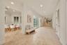 Open interior featuring large-format stone tile flooring, recessed lighting, double-paned glass French doors, and a staircase with a wrought-iron rail