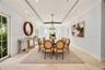 Tray ceiling with recessed lighting, stone flooring, multiple glass-paneled exterior doors, and a multi-arm chandelier