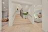 Grand foyer featuring a stone staircase with ornate iron railing, brass handrails, recessed wall niche, and natural stone flooring with recessed light