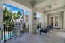 Covered patio featuring stone tile flooring, decorative wrought iron railings, an integrated ceiling fan, and recessed lighting
