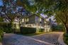 Two-story stucco exterior featuring architectural columns, multi-pane windows, arched entry, and a paver stone driveway