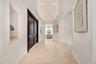 Foyer featuring stone tile flooring, double-door entry with brass hardware, oval tray ceiling with recessed lighting, and integrated wall niches
