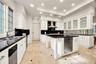 Kitchen featuring white shaker-style cabinetry, contrasting black countertops, a central island with integrated stainless steel dishwasher, recessed c