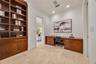 Custom wood-finish floor-to-ceiling cabinetry, integrated wooden built-in desk, stone tile flooring, and recessed ceiling lighting