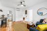 Terracotta tile flooring with inlaid decorative tiles, ceiling fan with integrated lighting, wall-mounted ductless air conditioning unit, and arched d
