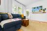 Bright living area featuring tile flooring, crown molding, double windows with blinds, and a built-in wall-mounted wooden shelf