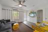 Neutral-toned wood-finish flooring, wall-mounted ductless mini-split HVAC unit, ceiling fan with integrated lighting, and an arched doorway