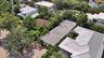 Aerial perspective of a multi-structure property featuring metal roof systems, paver driveway, and mature landscaping
