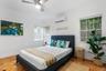 Neutral-toned room featuring terra-cotta tile flooring, a wall-mounted ductless air conditioning unit, a ceiling fan with integrated lighting, and mul
