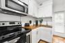 Kitchen featuring white cabinetry with metallic hardware, wood-finish countertops, stainless steel appliances, a hexagonal tile backsplash, and cerami