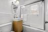Bathroom featuring a vanity with a rectangular vessel sink, sliding glass shower doors, subway-style wall tile, a barn-door style framed mirror, and a