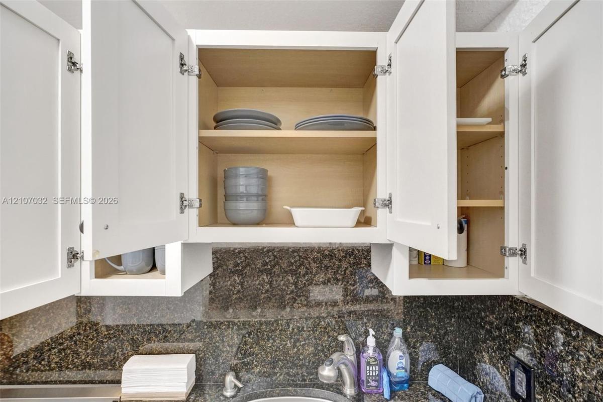 Shaker-style white cabinetry with adjustable shelving and a dark stone-finish backsplash