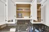 Shaker-style white cabinetry with adjustable shelving and a dark stone-finish backsplash