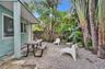 Exterior patio space featuring a gravel ground surface, privacy fencing, and established tropical vegetation