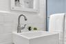 Wall-mounted square sink featuring a brushed nickel high-arc faucet and matte white tiled backsplash