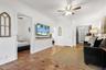 Interior space featuring terracotta tile flooring, crown molding, a ceiling fan with integrated lighting, and a wall-mounted wooden shelf