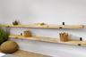 Dual natural wood shelving with matte black metal brackets mounted on a white textured wall