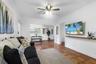 Living space featuring terracotta tile flooring, crown molding, a central ceiling fan with integrated lighting, and a wall-mounted wooden display shel