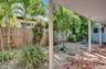 Covered patio featuring decorative tile flooring, gravel landscaping, established palms, and a wood privacy fence