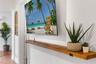 Wall-mounted wood floating shelf with matte black metal brackets and textured white wall finish