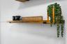 Wall-mounted natural wood shelving featuring matte black metal support brackets