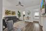 Living space featuring wood-finish flooring, a ceiling fan, and a wall-mounted television shelf