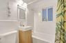 Bathroom featuring a wall-mounted vanity with a rectangular basin, subway tile wainscoting, sliding barn-door style mirror, and a built-in bathtub wit
