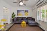 Living area featuring wood-finish flooring, a wall-mounted ductless climate control unit, and a ceiling fan with integrated lighting