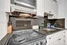 Kitchen featuring white cabinetry, dark stone countertops, integrated backsplash, stainless steel electric range, and an under-mounted sink
