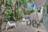 Private outdoor space featuring gravel ground cover, mature tropical landscaping, a perimeter wall, and an exterior storage structure
