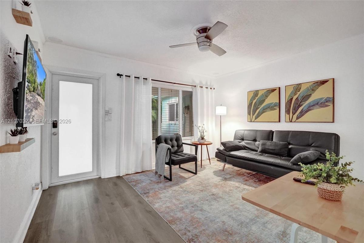 Living area featuring wood-finish flooring, a ceiling fan, and a glass-panel exterior door