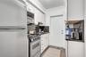 Kitchen featuring white shaker-style cabinetry, stainless steel appliances, dark stone-finish countertops, and wood-finish flooring