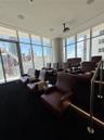 Floor-to-ceiling windows, tiered seating platform with integrated stair lighting, ceiling-mounted projection system, and recessed overhead lighting