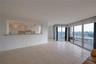 Open-concept living space with tile flooring, pass-through kitchen counter, recessed lighting, and expansive floor-to-ceiling glass sliding doors lead