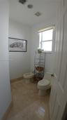 Neutral-toned stone flooring, one-piece dual-flush toilet, bidet, and single-pane window with top-down shade