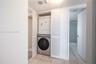 Laundry closet featuring white louvered bifold doors, stacked appliance configuration, and tile flooring