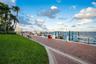 Waterfront promenade featuring a herringbone-patterned paver path, manicured lawn, and multiple deep-water boat slips