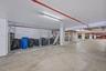 Covered parking area featuring concrete flooring, chain-link storage lockers, and overhead lighting
