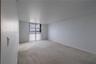 Neutral-toned interior space featuring light-colored wall-to-wall carpeting, expansive wall space, and a floor-to-ceiling window configuration