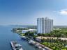 High-rise residential building featuring private boat slips, manicured landscaping, paved walkways, and direct water frontage