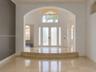 Entryway featuring stone tile flooring, a two-step raised landing, a vaulted arched entryway, double-door entry with sidelights, and an arched transom