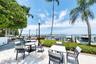 Waterfront patio featuring stone paver flooring, integrated landscape lighting, established palm trees, and a private boat dock