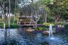 Water feature with dual fountains, pond, wood-framed gazebo, mature trees, and landscaped stone edging