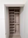 Built-in closet featuring light wood-finish shelving, multiple open storage compartments, and a horizontal hanging rod