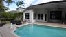 Rear exterior featuring an in-ground swimming pool, concrete paver patio, covered porch with a ceiling fan, and stucco siding